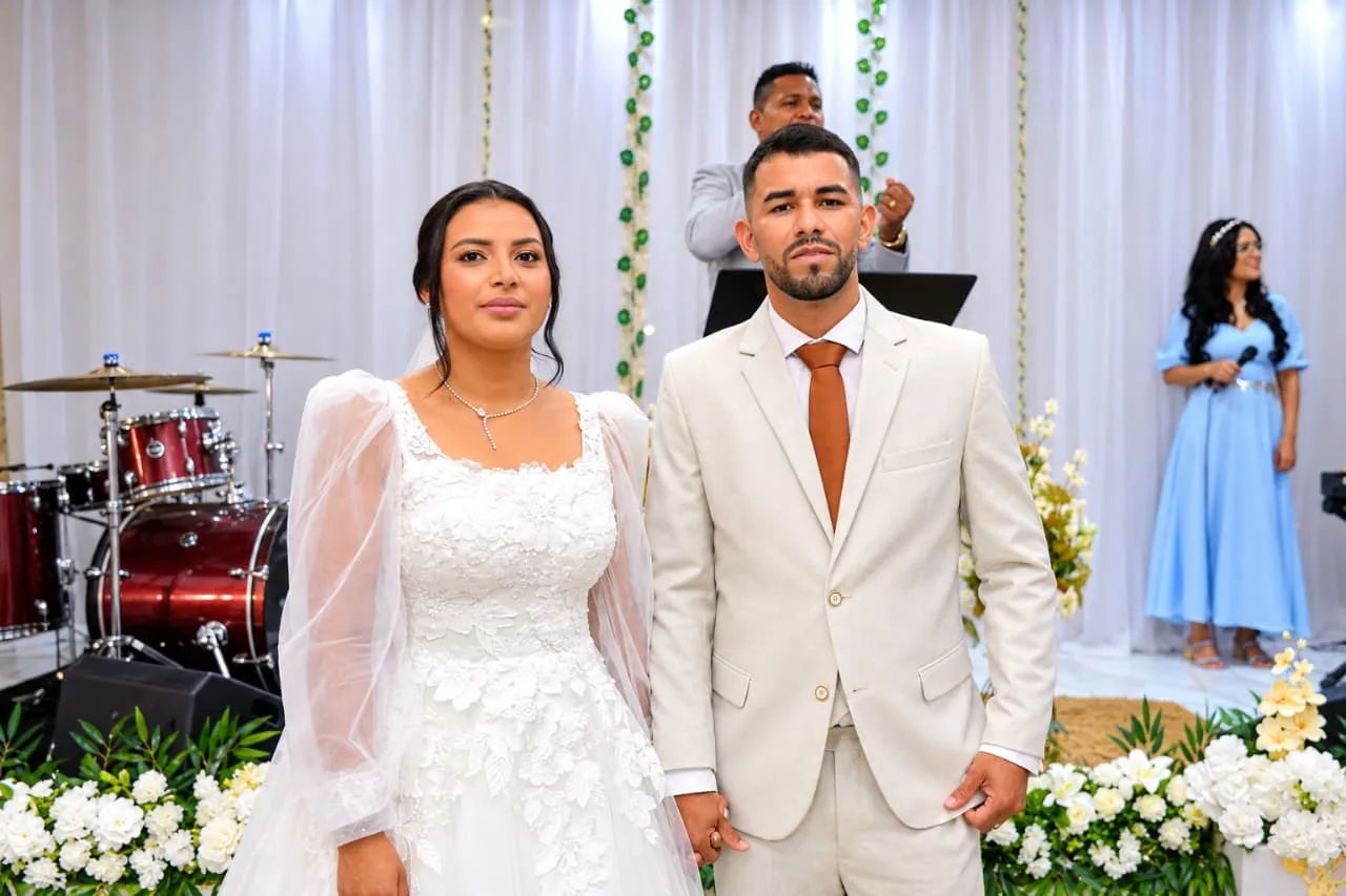 Noivos de mãos dadas em cerimônia com decoração floral branca