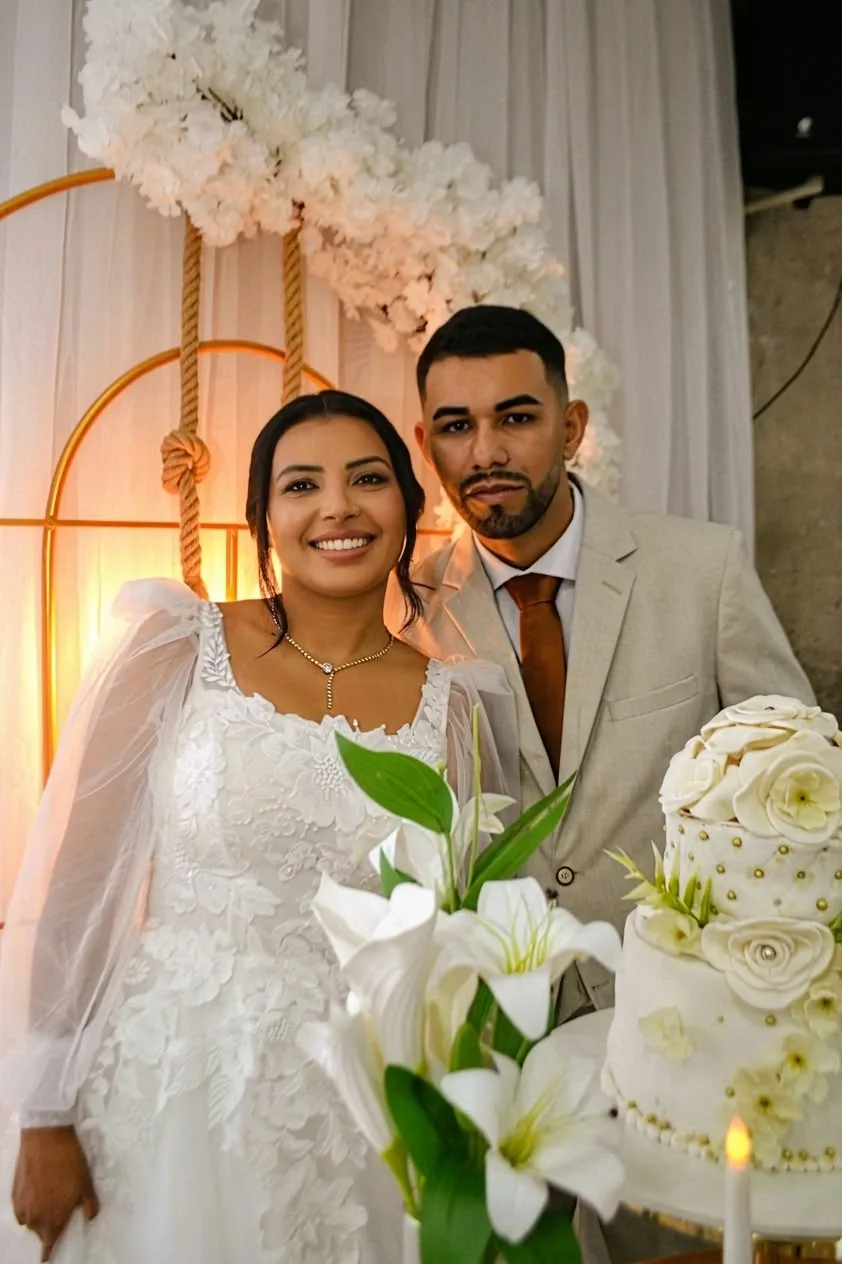 Retrato dos noivos junto a flores brancas e bolo de casamento